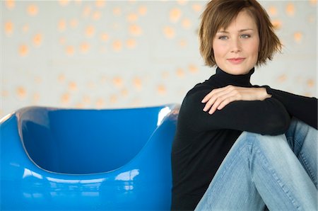 simsearch:6108-05859747,k - Young woman sitting on the floor, leaning against blue armchair Stock Photo - Premium Royalty-Free, Code: 6108-05856453