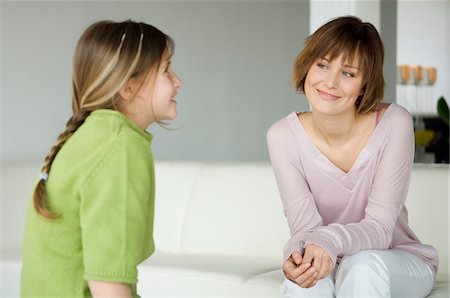 Smiling woman and little girl sitting in living-room Stock Photo - Premium Royalty-Free, Code: 6108-05856591