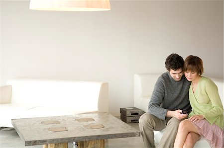 simsearch:6108-05857751,k - Couple sitting on a sofa in living-room,using mobile phone Stock Photo - Premium Royalty-Free, Code: 6108-05856698