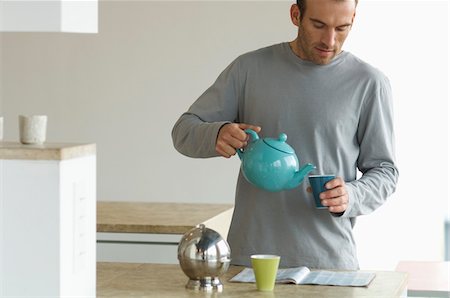simsearch:6108-05856772,k - Man standing in the kitchen, pouring tea into a glass Stock Photo - Premium Royalty-Free, Code: 6108-05856771