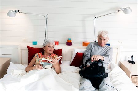 simsearch:6108-05856772,k - Senior couple in bed, woman reading, man playing video game Stock Photo - Premium Royalty-Free, Code: 6108-05856872