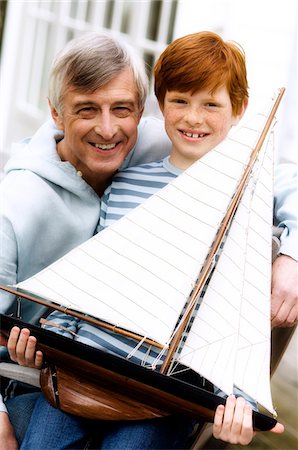 Senior man and boy holding a model boat, outdoors Stock Photo - Premium Royalty-Free, Code: 6108-05856880
