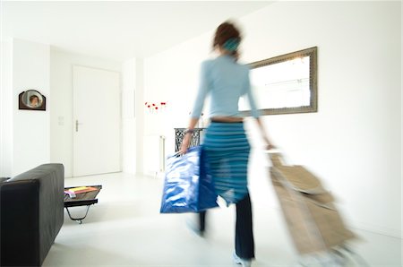 shopping cart - Woman carrying a bag and a shopping trolley in a living-room Foto de stock - Sin royalties Premium, Código: 6108-05857101
