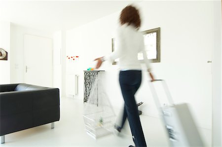 Woman carrying suitcase and birdcage in a living-room Stock Photo - Premium Royalty-Free, Code: 6108-05857111