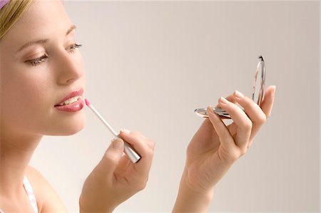 Portrait d'une jeune femme maquillage sa bouche, à l'intérieur (studio) Photographie de stock - Premium Libres de Droits, Code: 6108-05857365