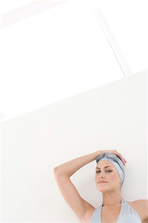 Portrait of a young woman with bikini, swimming cap and goggles, hand on head Stock Photo - Premium Royalty-Free, Code: 6108-05857474