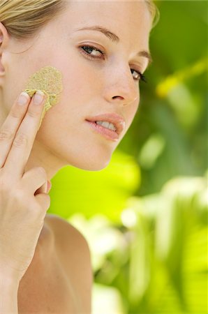 Young woman applying face scrub cream on her face, outdoors Stock Photo - Premium Royalty-Free, Code: 6108-05857543