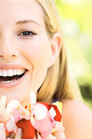 simsearch:6108-05857519,k - Portrait of a young  blond woman smiling, holding petals, outdoors Stock Photo - Premium Royalty-Free, Code: 6108-05857570