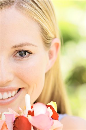 simsearch:6108-05857519,k - Portrait of a young  blond woman smiling, holding petals, outdoors Stock Photo - Premium Royalty-Free, Code: 6108-05857581