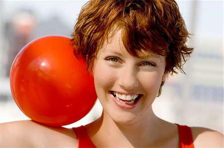 red haired woman - Portrait of a young smiling woman, red ball on shoulder Stock Photo - Premium Royalty-Free, Code: 6108-05857506