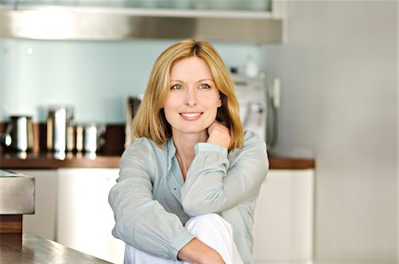 emotional happy - Smiling woman sitting in kitchen Stock Photo - Premium Royalty-Free, Code: 6108-05857680