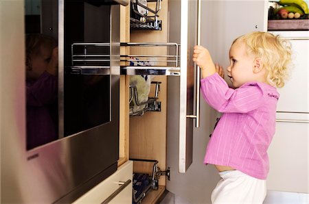 Little girl opening cabinets in kitchen, indoors Stock Photo - Premium Royalty-Free, Code: 6108-05857990