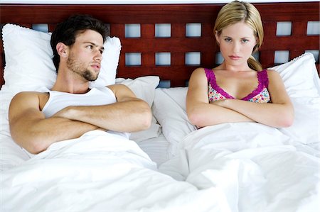 Young couple in bed, arms crossed Stock Photo - Premium Royalty-Free, Code: 6108-05857902