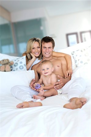 simsearch:6108-05860153,k - Young couple and baby in living room, looking at the camera, indoors Stock Photo - Premium Royalty-Free, Code: 6108-05857920