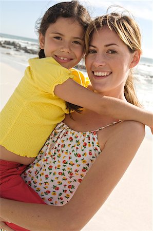 simsearch:6108-05858128,k - Portrait of a mother carrying her daughter, smiling, posing for the camera, outdoors Stock Photo - Premium Royalty-Free, Code: 6108-05858126