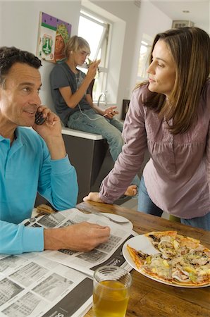 Parents and teenager in living room, pizza on table, indoors Stock Photo - Premium Royalty-Free, Code: 6108-05858276