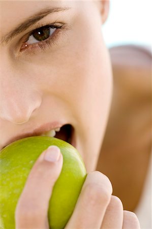 Portrait of a young woman eating an apple, indoors Stock Photo - Premium Royalty-Free, Code: 6108-05858353