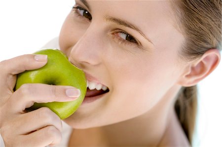 simsearch:6108-05865577,k - Portrait of a young woman eating an apple, indoors Stock Photo - Premium Royalty-Free, Code: 6108-05858326