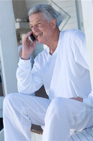 simsearch:6108-05857751,k - Man using mobile phone sitting on wooden terrace Stock Photo - Premium Royalty-Free, Code: 6108-05858715