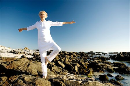 Senior woman doing yoga on seaside rocks Stock Photo - Premium Royalty-Free, Code: 6108-05858840