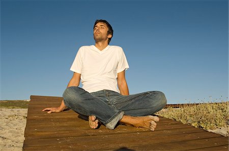 simsearch:6108-05858292,k - Young man sitting cross-legged, outdoors Stock Photo - Premium Royalty-Free, Code: 6108-05859041