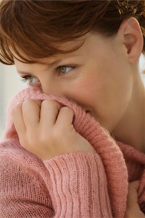 Portrait of young woman covering her mouth with jumper Foto de stock - Sin royalties Premium, Código: 6108-05859072