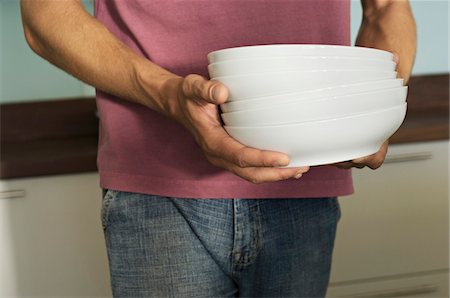 stacked dishes - Young man carrying stack of plates Stock Photo - Premium Royalty-Free, Code: 6108-05859036