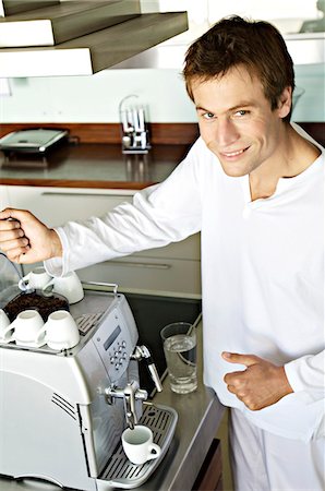 simsearch:6108-05856772,k - Young smiling man in front of espresso maker Stock Photo - Premium Royalty-Free, Code: 6108-05859039