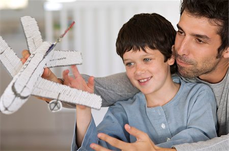 Father and son playing with model aeroplane Stock Photo - Premium Royalty-Free, Code: 6108-05859204