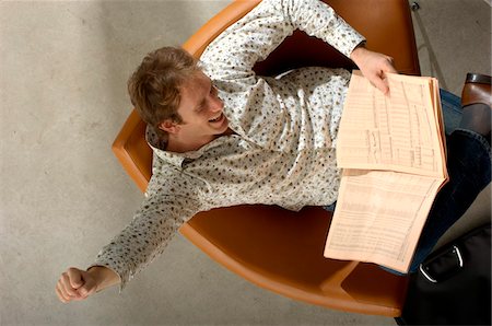 simsearch:6108-05856772,k - Young man reading newspaper, high angle view Stock Photo - Premium Royalty-Free, Code: 6108-05859381