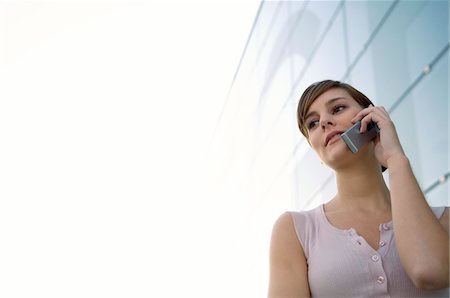 Low angle view of a young woman talking on a mobile phone Stock Photo - Premium Royalty-Free, Code: 6108-05859639