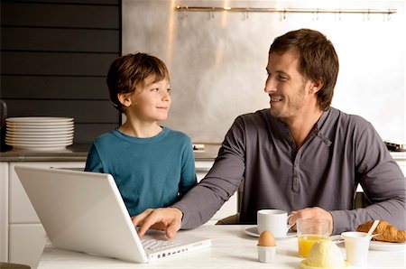 simsearch:6108-05864945,k - Mid adult man using a laptop and looking at his son Stock Photo - Premium Royalty-Free, Code: 6108-05859878