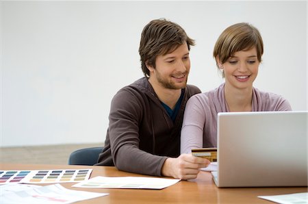 ecommerce - Mid adult man and a young woman using a laptop and holding a credit card Stock Photo - Premium Royalty-Free, Code: 6108-05860077