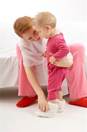 family shoes - Young woman putting baby booties to her son Stock Photo - Premium Royalty-Free, Code: 6108-05860153