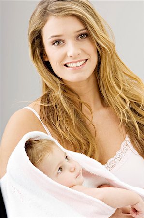 simsearch:6108-05860153,k - Portrait of a young woman wrapping her son in a towel and smiling Stock Photo - Premium Royalty-Free, Code: 6108-05860184