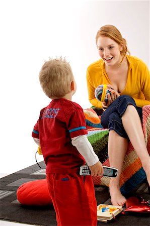 Young woman sitting on a couch and playing with her son Stock Photo - Premium Royalty-Free, Code: 6108-05860195