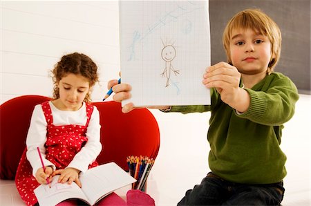 simsearch:6108-05860263,k - Portrait of a boy showing a drawing with his sister sitting in the background Stock Photo - Premium Royalty-Free, Code: 6108-05860276