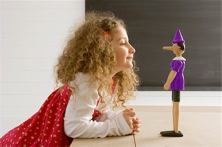 playing with toys - Side profile of a girl playing with a toy Stock Photo - Premium Royalty-Free, Code: 6108-05860218