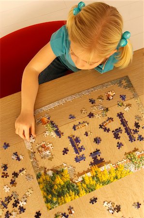 High angle view of a girl playing a jigsaw puzzle Stock Photo - Premium Royalty-Free, Code: 6108-05860227