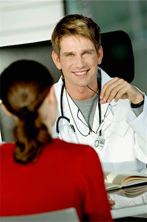 physician consulting backview - Portrait of a male doctor discussing with a female patient in his office Stock Photo - Premium Royalty-Free, Code: 6108-05860334