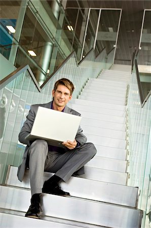 Portrait of a businessman sitting on a staircase and using a laptop Stock Photo - Premium Royalty-Free, Code: 6108-05860470