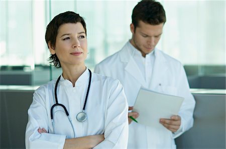 emotional woman looking away - Female doctor standing with a male doctor holding medical records behind her Stock Photo - Premium Royalty-Free, Code: 6108-05860401