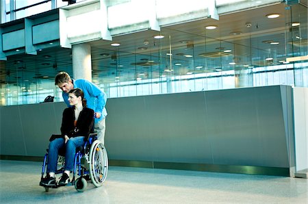 pushing - Mid adult man pushing a young woman sitting in a wheelchair Stock Photo - Premium Royalty-Free, Code: 6108-05860421