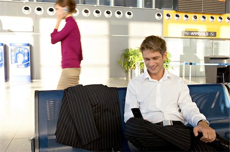 simsearch:6108-05860554,k - Businessman using a mobile phone at an airport lounge Stock Photo - Premium Royalty-Free, Code: 6108-05860555