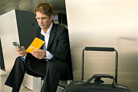 simsearch:6108-05860554,k - Businessman sitting at an airport and operating a mobile phone Stock Photo - Premium Royalty-Free, Code: 6108-05860565