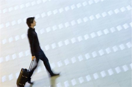 simsearch:6108-05860448,k - High angle view of a man pulling his luggage at an airport lobby Foto de stock - Sin royalties Premium, Código: 6108-05860583