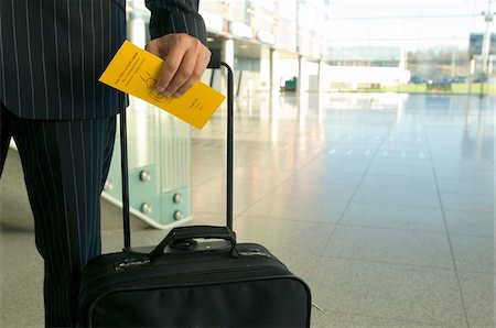 simsearch:6108-05860448,k - Mid section view of a businessman holding a luggage and an airplane ticket Foto de stock - Sin royalties Premium, Código: 6108-05860581