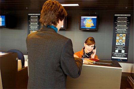 simsearch:6108-05860448,k - Rear view of a businessman standing at an airport check-in counter and the check-in attendant talking on the telephone Foto de stock - Sin royalties Premium, Código: 6108-05860586