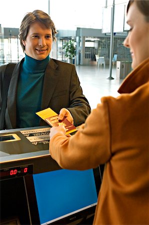 simsearch:6108-05860554,k - Businessman with a female check-in attendant at an airport check-in counter Stock Photo - Premium Royalty-Free, Code: 6108-05860532