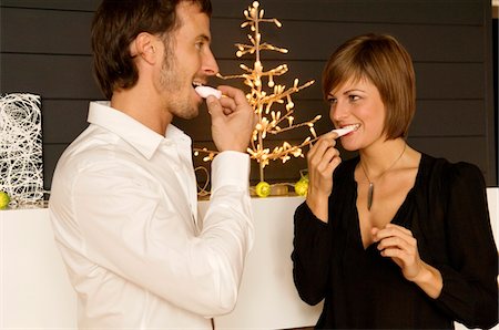 party decoration - Mid adult man and a young woman eating candies Stock Photo - Premium Royalty-Free, Code: 6108-05860685